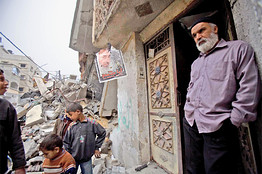 A poster of the late Sheikh Yassin hangs near a building destroyed by the Israeli assault on Gaza.
